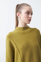 Polera de tejido de punto color marrón, con diseño asimétrico y costura diagonal frontal. Presenta cuello alto, hombros caídos, mangas largas con puños acanalados y ruedo con abertura frontal.