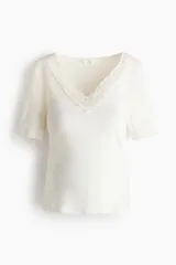 Top de jersey acanalado color blanco off-white, con escote en V profundo adornado con encaje y mangas cortas.