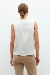 Blusa de satén color blanco, sin mangas, con cuello redondo y diseño fluido.