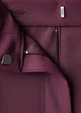 Pantalón de vestir bordó de tiro medio, con diseño wide leg, pinzas en la parte delantera, bolsillos laterales y cierre frontal con botón, gancho y cremallera.