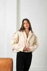 Campera de gamuza color beige, con diseño tipo globo, cuello camisero, cierre frontal y mangas amplias.