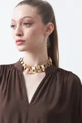 Blusa de manga larga color marrón oscuro, con escote en V y cuello mao. Presenta frunces en el canesú y puños ajustados.