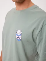 Remera Rusty de corte holgado, color amarillo, con estampa en la espalda de un personaje surfeando sobre un pez y textos descriptivos.