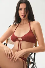 Bikini de textura rugosa en color terracota, con corpiño triangular de estilo halter que presenta un detalle de lazo central y bombacha con tiras laterales ajustables.