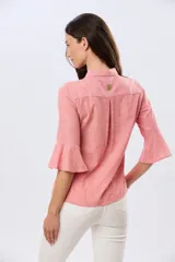 Camisa de lino celeste con cuello clásico, cierre frontal con botones y mangas tres cuartos terminadas en volados.