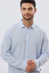 Camisa de manga larga confeccionada en mezcla de lino y algodón, con sutiles rayas celestes, cuello camisero clásico y cierre frontal de botones.