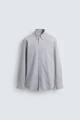 Camisa de corte regular fit confeccionada en tejido de algodón con estampado de microcuadros. Presenta cuello abotonado, manga larga con puños abotonados y cierre frontal de botones.