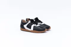 Zapatillas Magnolia de cuero negro con detalles en blanco y suela marrón.