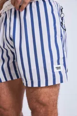 Short de baño con estampado botánico en tonos tierra, rosados y verdes. Presenta cintura elástica con cordón ajustable y un pequeño parche con logo en el ruedo.