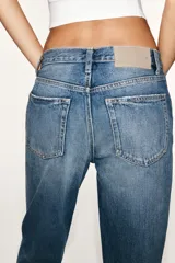 Jeans de tiro medio con corte straight, color azul con efecto lavado y roturas sutiles, cinco bolsillos y cierre frontal con cremallera y botón metálico.
