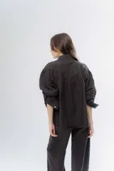 Camisa de algodón color beige con detalles de encaje y broderie en el canesú y las mangas. Presenta cuello camisero, cierre frontal con botones y mangas largas con puños.