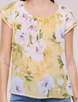 Blusa de gasa semitransparente color azul marino con estampado floral en tonos celestes y lilas, cuello redondo elastizado con lazo central y mangas cortas con doble volado.