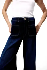 Jeans de tiro alto en denim de algodón con leve stretch, corte wide leg de piernas amplias, bolsillos parche delanteros y raya marcada en el frente.