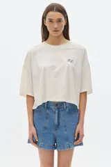 Remera color crudo de algodón lavado, corte cropped y mangas cortas. Presenta un pequeño bordado con las iniciales "PS" en el pecho.