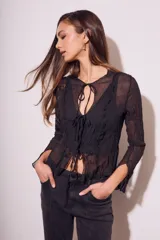 Blusa negra traslúcida de viscosa con textura arrugada, mangas largas acampanadas y escote en V con lazos.
