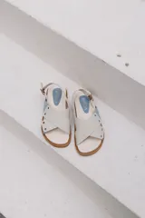 Sandalias planas color celeste y blanco, con tiras anchas cruzadas y suela color caramelo.
