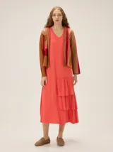 Vestido midi de morley color coral, con escote en V, sin mangas y diseño holgado con volados fruncidos en el lateral de la falda.