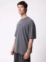 Remera oversize de color gris oscuro con efecto acid wash, mangas cortas y cuello redondo. Cuenta con un pequeño estampado frontal con la inscripción "DIXIE".
