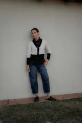 Cardigan bicolor blanco y negro con escote en V, cierre frontal de botones y ribetes negros en cuello, puños y ruedo.