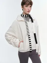 Campera de tela fleece doble, color blanco, con cierre frontal, cuello alto y bolsillos laterales. Diseño holgado con puños y bajo elastizados.