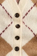 Saco tipo cárdigan de punto jacquard con diseño de rombos, escote en pico, cierre frontal con botones y hombros caídos. Presenta terminaciones acanaladas en cuello, puños y ruedo.