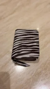 Billetera de cuero de pelo con estampado animal print de leopardo. Cuenta con cierre perimetral y una etiqueta de cuero con el logo de la marca grabado.