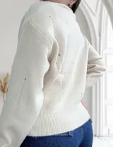 Sweater color crudo de tejido de punto con cuello redondo y detalles de roturas.