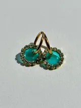 Aros de acero quirúrgico con dije circular de resina rosa y borde de strass dorados.