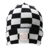 Gorro tipo beanie tejido con diseño de damero en blanco y negro. Presenta un parche frontal de tela con la inscripción circular en color rosa.