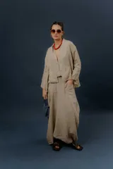 Pollera larga de lino color gris topo, de diseño amplio con volumen, movimiento y bolsillos delanteros. Cuenta con elástico en la cintura y detalles de pinzas y sobretelas en los laterales.
