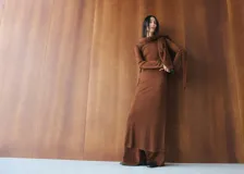 Vestido midi de punto color marrón, de corte recto, manga larga y cuello redondo con bufanda integrada del mismo tejido.