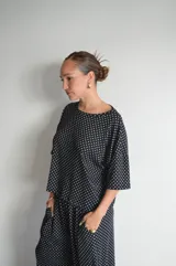 Pantalón negro de algodón y viscosa, con estampado de lunares blancos y corte holgado.