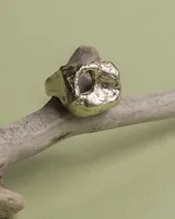 Anillo dorado con forma irregular y un agujero en el centro.