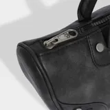 Bolso tipo bowling Adidas de color negro con efecto desgastado, diseño estructurado y asas de hombro. Presenta detalles de tachuelas metálicas en los laterales frontales y el logotipo del trébol grabado en el centro.