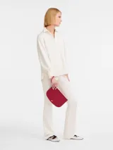Clutch o pouch de mano Longchamp modelo Epure, color rojo cereza, con forma curva y cierre de solapa con broche dorado.