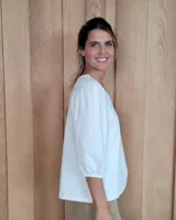 Remera blanca con cuello en V, cuerpo de algodón y mangas abullonadas de encaje bordado con puños elásticos.