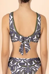 Top de bikini con escote en V profundo, diseño de estampado orgánico en tonos verde y violeta sobre fondo blanco, con ribetes en color verde oliva.