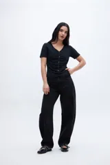 Remera negra con escote en V, cartera de botones, frunces y mangas cortas.