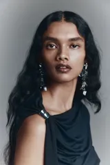 Top negro de punto elástico con escote asimétrico de un hombro, detalle de metal plateado y tira larga. Diseño entallado con laterales fruncidos para crear un efecto drapeado.