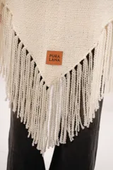 Ruana artesanal color crema, tejida en telar manual con lana merino. Tiene hilado mecha, textura rústica y bolsillos de cuero natural.