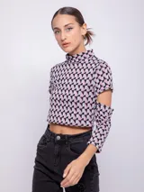 Top corto de tejido con estampado geométrico retro en tonos rosa, gris y negro. Es de manga larga con cut-out en los codos y cuello alto.