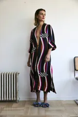 Kimono largo hasta el tobillo, con estampado de rayas verticales en negro, blanco, fucsia, naranja y violeta. Presenta detalles de labios geométricos en blanco y negro.