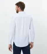 Camisa de corte comfort, manga larga con cuello camisero y cierre frontal de botones. Presenta un estampado de cuadros tipo grid en tonos claros sobre fondo blanco.