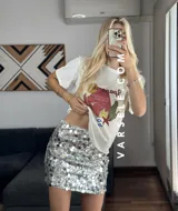 Remera blanca de cuello redondo y manga corta con estampado de paisaje costero en tonos naranja, rojo, verde y azul.