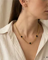Collar de cadena tipo eslabón grueso con baño de oro, que presenta tres dijes circulares con piedra ónix negra y detalles de números romanos en los bordes.