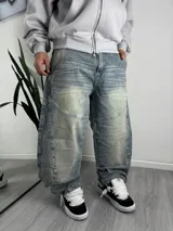Pantalón jean baggy de corte ancho y relajado, con efecto acid wash y lavado desgastado en tono celeste. Presenta costuras reforzadas y paneles frontales en las rodillas.