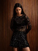 Mini falda negra de lentejuelas con diseño de volado en el ruedo, confeccionada en tejido con spandex.