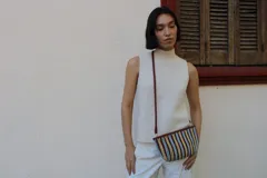 Cartera tipo sobre confeccionada en cuero trenzado a mano, con diseño de rayas verticales en tonos negro y natural.