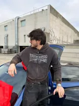 Campera canguro con cierre frontal, capucha y bolsillos tipo canguro, en tono marrón con efecto gastado vintage y estampa gráfica blanca con detalles de strass en el pecho.