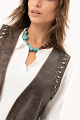 Chaleco de cuero marrón con silueta relajada, caracterizado por detalles de ojalillos metálicos a lo largo de los bordes frontales.